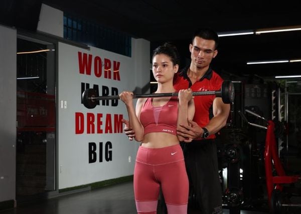 Huấn luyện viên cá nhân PT đang hướng dẫn học viên tập gym đúng tư thế tại phòng tập